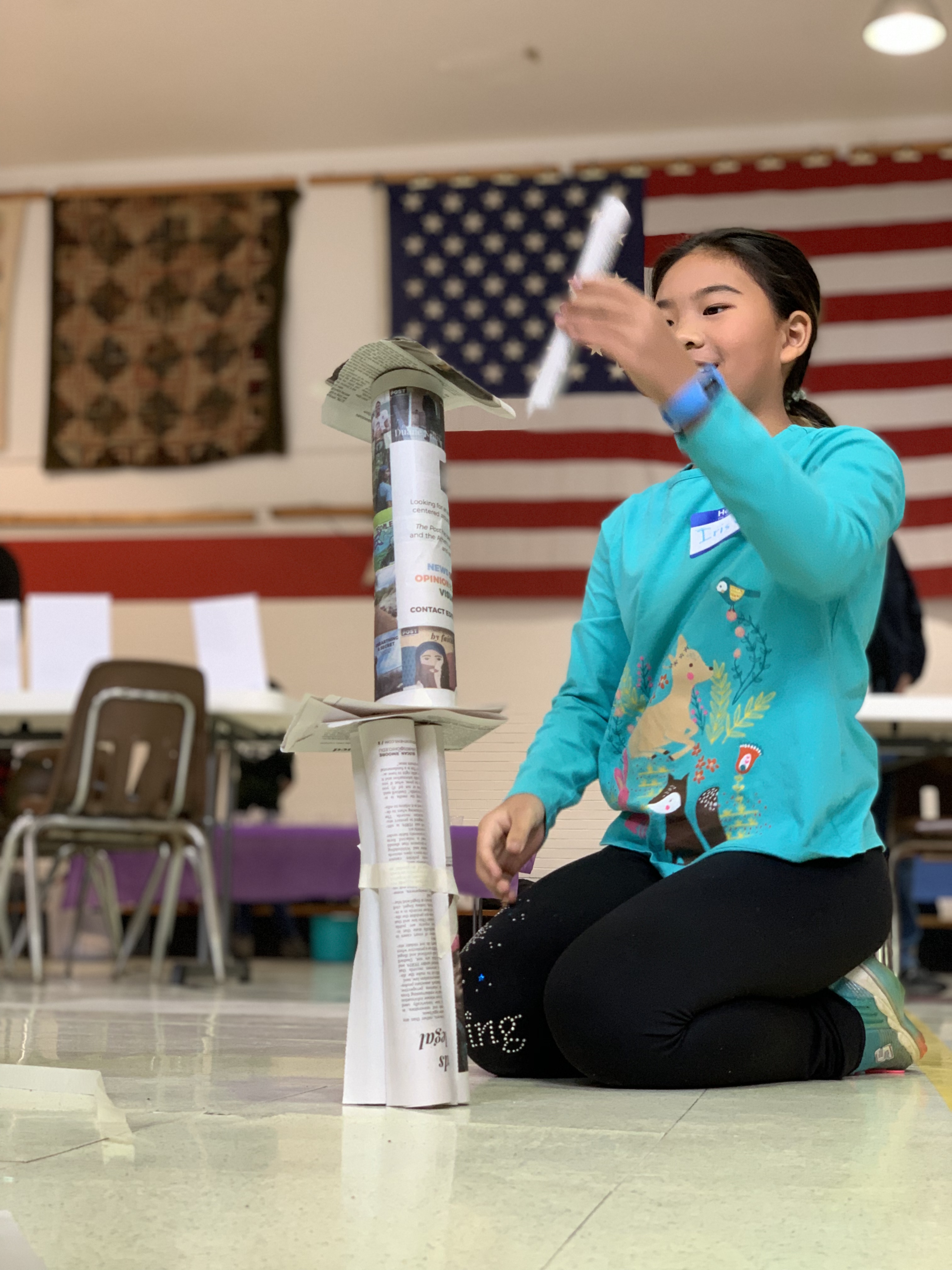 A youth builds a tower with newspaper