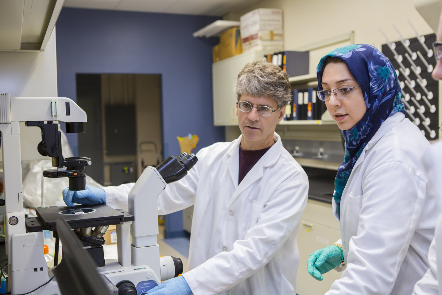 Dr. Doug Goetz and an associate, wearing white coats, use lab equipment